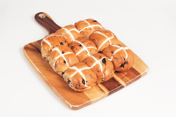 Hot cross buns on a timber board with a white background.