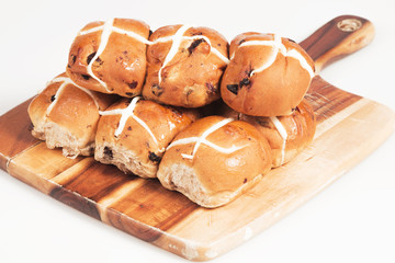 Hot cross buns on a timber board with a white background.
