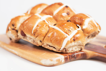 Hot cross buns on a timber board with a white background.