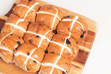 Hot cross buns on a timber board with a white background.