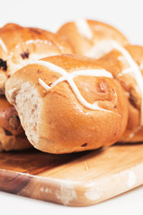 Hot cross buns on a timber board with a white background.