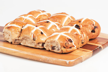 Hot cross buns on a timber board with a white background.