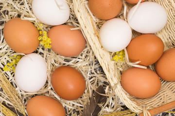Chicken eggs in a wicker basket and straw