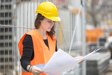 Young attractive female architect at construction site. Outdoors