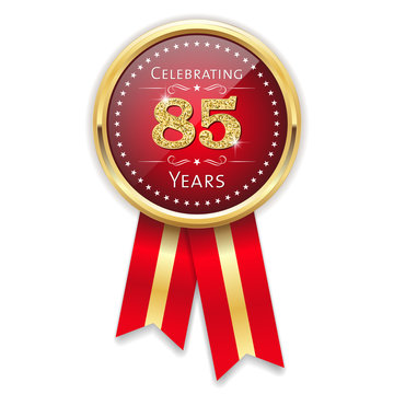 Red celebrating 85 years badge, rosette with gold border and ribbon