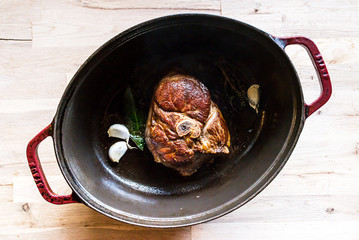 cooking a beautiful grilled slice of an organic leg of lamb meat in a a cooking pot with garlic,...