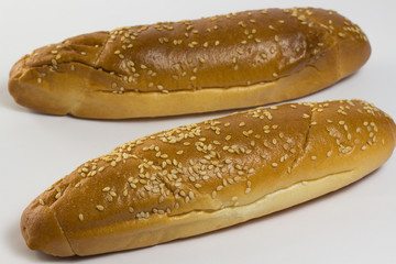 Two baguette sprinkled with sesame seeds on a white background