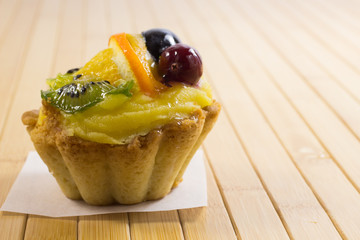 Cake with slices of kiwi, tangerine and berries two cherries on