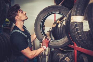 Professional car  mechanic choosing new tire in auto repair service.