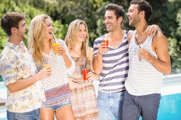 Group of happy friends having juice near pool
