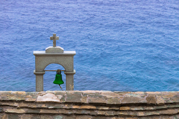 A bell tower is looking the aegean sea.