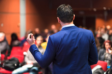 Speaker giving a talk on corporate Business Conference. Audience at the conference hall. Business...