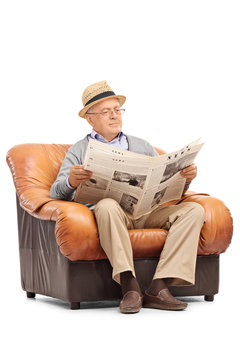 Senior reading a newspaper seated on armchair