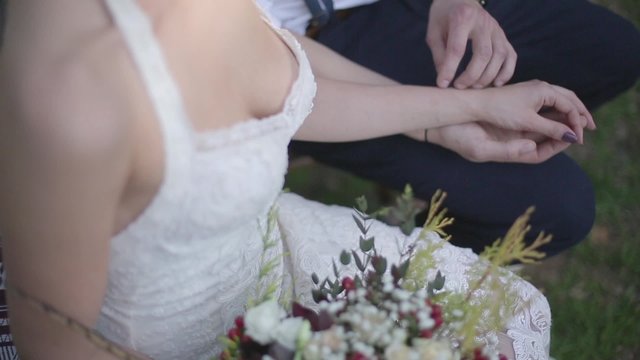 Bride sitting with flowers and holding the hand of the groom.