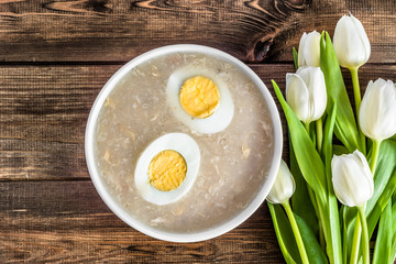 Traditional easter soup white borscht with eggs on wooden table