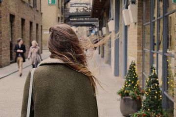 Young girl with dispelled hair walking down the street in the wind