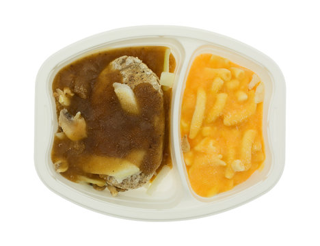 Frozen Salisbury steak TV dinner in white plastic tray isolated on a white background top view.