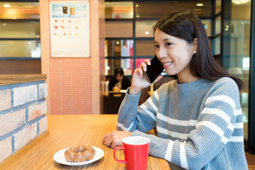 Woman talk to cellphone and enjoy her breakfast in coffee shop