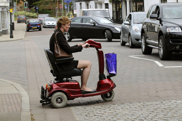 Woman seated on a mobility scooter crosses the road at a pedestrian crossing