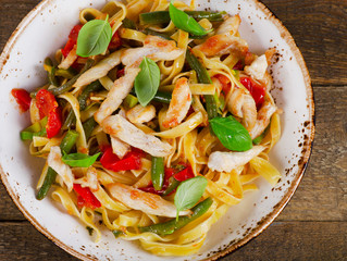 Italian Pasta with chicken and vegetables on  wooden table.
