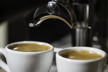 two cups of espresso poured from a espresso machine 