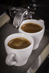 two cups of espresso poured from a espresso machine 