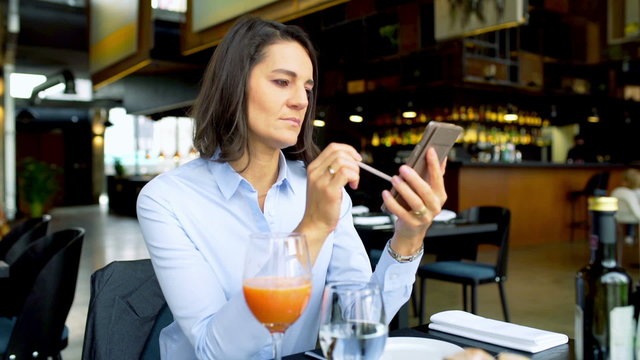Businesswoman browsing internet on smartphone in the cafe, steadycam shot

