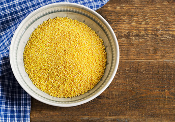Organic millet in a bowl on a wooden rustic table.