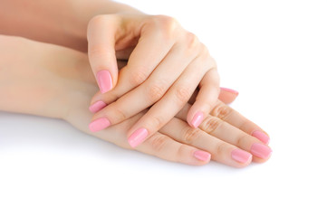 Closeup of hands of a young woman with pink manicure on nails against white background