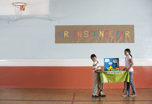 Boy and girl carrying table with presentation on solar energy