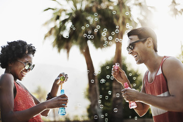 Two people blowing bubbles using bubble wands, 