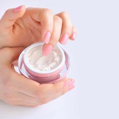 Hands of a woman with pink manicure with cream