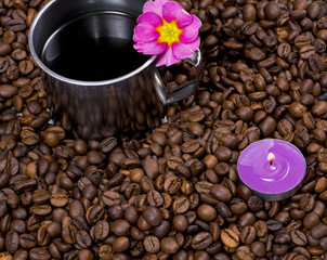 Fototapeta na wymiar lilac candle and steel cup of coffee in coffee grains