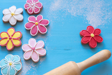 Happy Easter  (home-baked cookies) 
Flower shaped gingerbread cookies and rolling pin on a blue wooden table.
