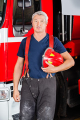 Naklejka premium Confident Firefighter Holding Red Helmet