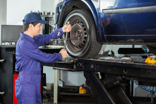 Mechanic Fixing Car Tire At Repair Shop