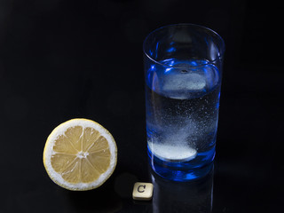 Vitamin C tablet bubbles in glass of water and lemon