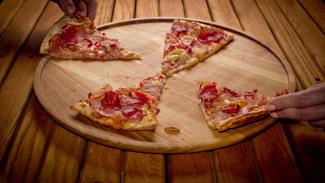 Top view hands taking big pizza cuts from wooden  plate on the table - stop motion animation, 4K