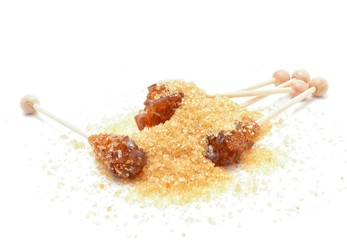 Brown sugar crystal on wooden stick and brown granulated sugar on a white background