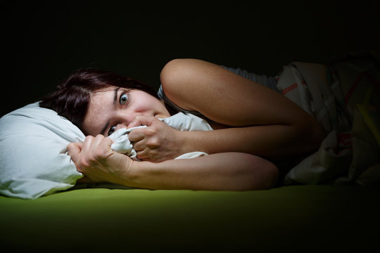 Young woman in bed with eyes opened suffering insomnia. Sleeping concept and nightmare issues