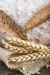 Hogaza de pan de cereales variados sobre arpillera r&uacute;stica con espigas de trigo y centeno para la comida