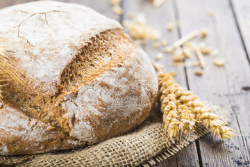 Hogaza de pan de cereales variados sobre arpillera rústica con espigas de trigo y centeno para la...