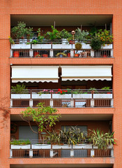 Balconies of a brick building, decorated with flowers and plants in pots. Vertical view.
