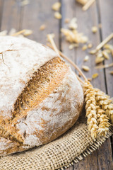 Hogaza de pan de cereales variados sobre arpillera rústica con espigas de trigo y centeno para la...
