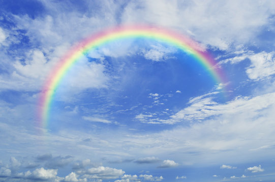 Rainbow with white clouds over blue sky