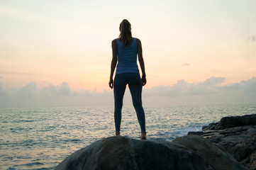 the beautiful girl sitting on stones and looking in a distance, the girl at sunset to meditate in silence, beautiful body .concept .Siluet lonely girl sitting on the precipice of a cliff at sunset. 