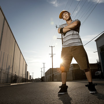 A young man, a breakdancer standing on a street with arms folded,