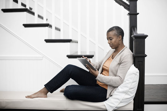 Mature woman seating in hallway using digital tablet