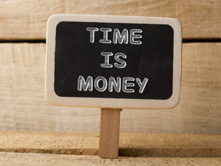 Time is money concept. Wooden sign on wood background