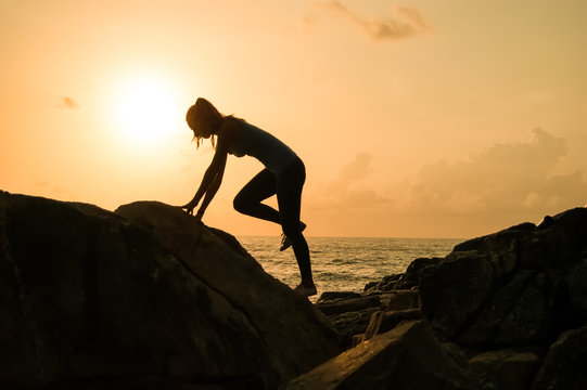 the young beautiful girl the sportswoman, in sportswear sneakers jumps through rocks at sunset, a high jump, physical training, fitness the instructor, an extreme sport, parkour, 
